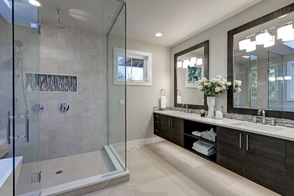 A modern bathroom with a walk-in shower and double sinks, featuring glass cleaner and maintenance for glass objects