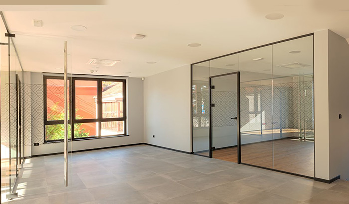 A room with glass walls and stairs, showcasing large glass doors and glass maintenance