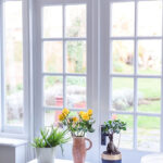 A white window with a table and a vase of flowers